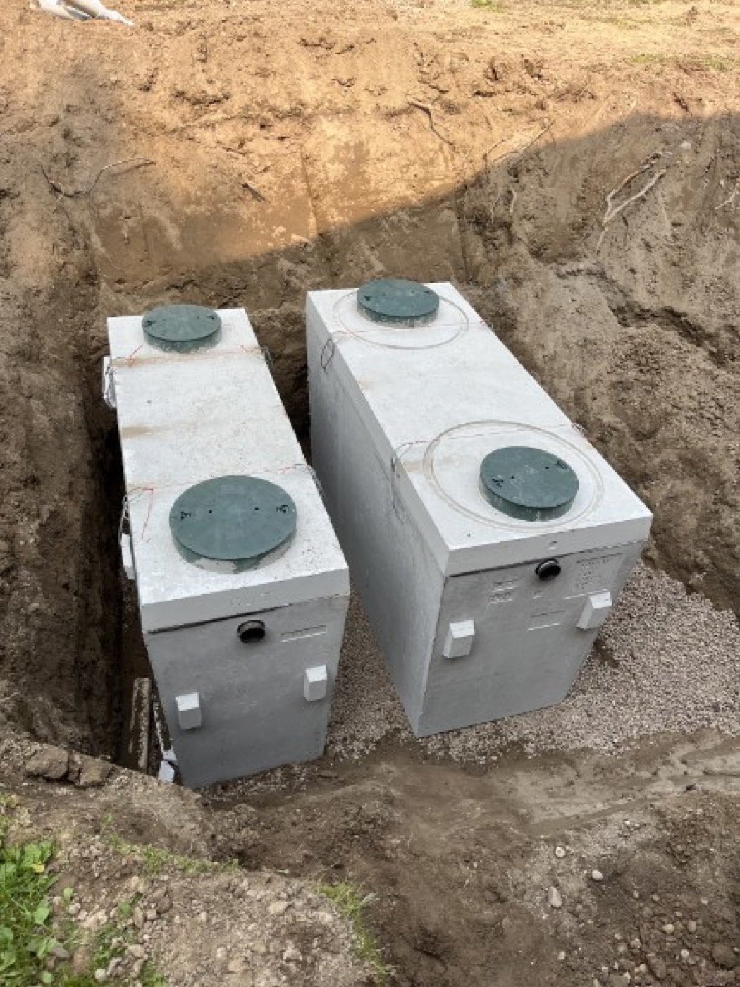 Two concrete septic tanks positioned within an excavated area